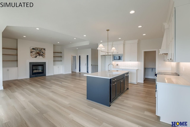 kitchen with white cabinets, sink, a kitchen island with sink, decorative light fixtures, and stainless steel appliances