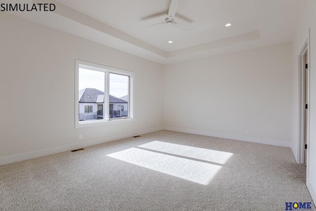 carpeted empty room featuring ceiling fan and a tray ceiling