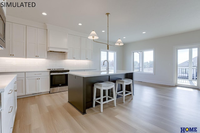 kitchen featuring a center island with sink, stainless steel appliances, light hardwood / wood-style floors, and a wealth of natural light