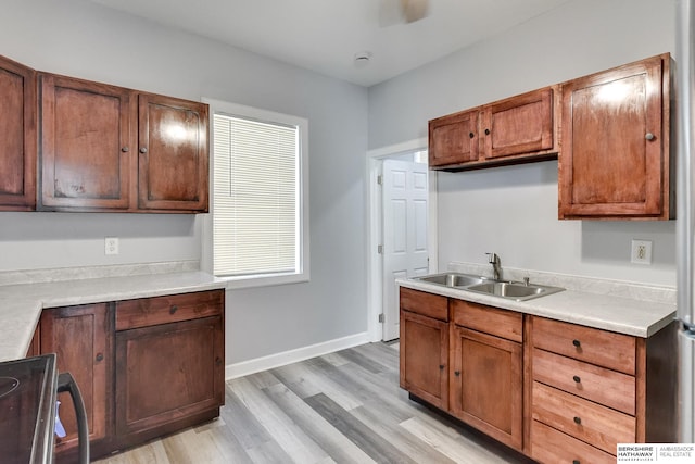 kitchen with light wood-type flooring, sink, and range