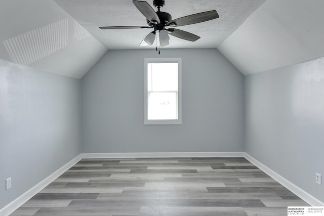 additional living space with a textured ceiling, lofted ceiling, ceiling fan, and light hardwood / wood-style flooring