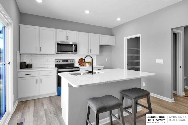 kitchen featuring white cabinets, appliances with stainless steel finishes, and a kitchen island with sink