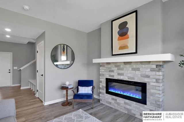 living room featuring a brick fireplace and light wood-type flooring