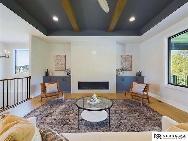 living room featuring a notable chandelier, beam ceiling, and hardwood / wood-style flooring