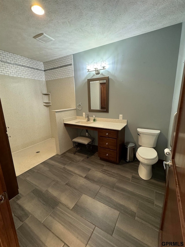 bathroom with walk in shower, sink, toilet, and a textured ceiling