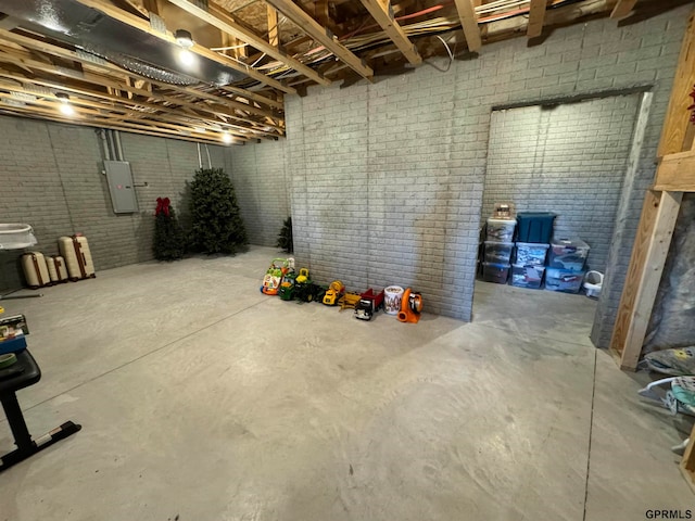 basement featuring electric panel and brick wall