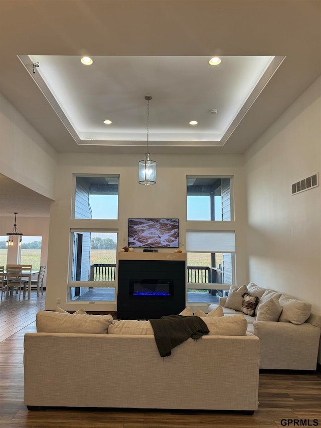 living room featuring a towering ceiling, a tray ceiling, and dark hardwood / wood-style floors