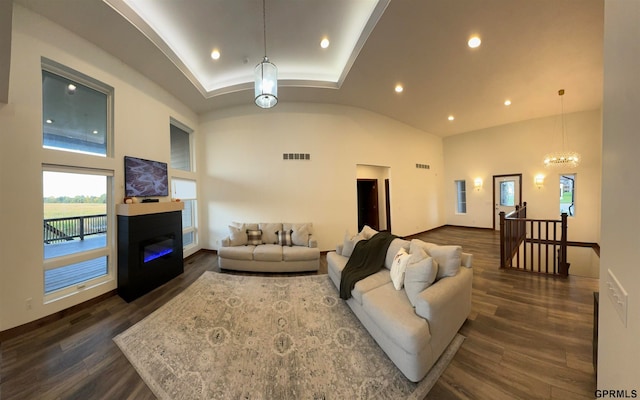 living room with high vaulted ceiling, a notable chandelier, and dark hardwood / wood-style floors