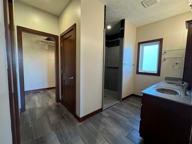 bathroom featuring walk in shower, vanity, a textured ceiling, and wood-type flooring