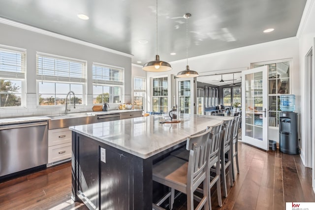 kitchen with light stone countertops, dishwasher, a kitchen island, pendant lighting, and decorative backsplash