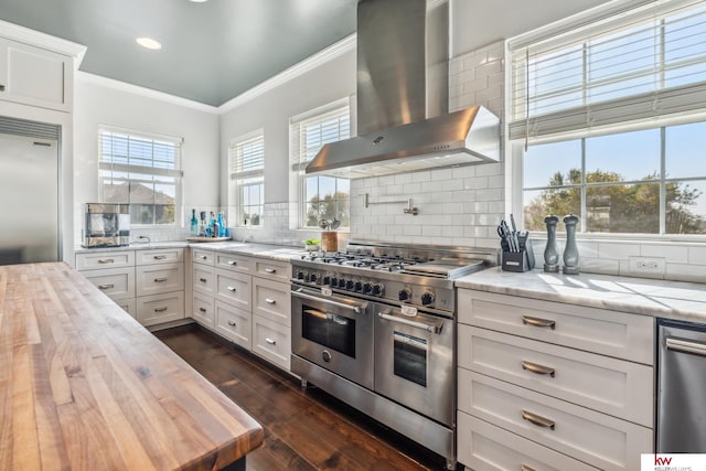 kitchen featuring wall chimney range hood, high quality appliances, butcher block countertops, white cabinets, and dark hardwood / wood-style floors