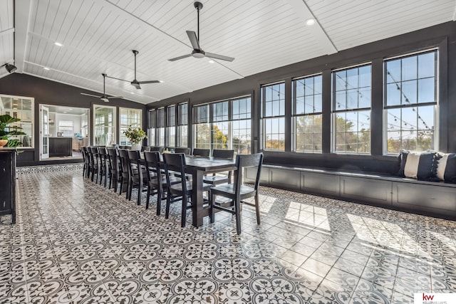 sunroom / solarium with lofted ceiling, wood ceiling, a healthy amount of sunlight, and ceiling fan