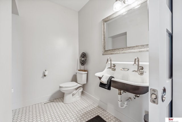 bathroom with toilet, sink, and tile patterned flooring