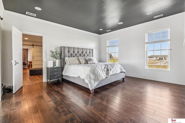 bedroom featuring multiple windows, a barn door, dark wood-type flooring, and crown molding