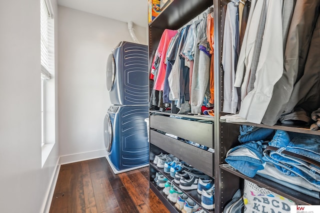 spacious closet with dark hardwood / wood-style floors and stacked washer and clothes dryer