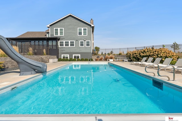 view of swimming pool with a water slide and a patio area