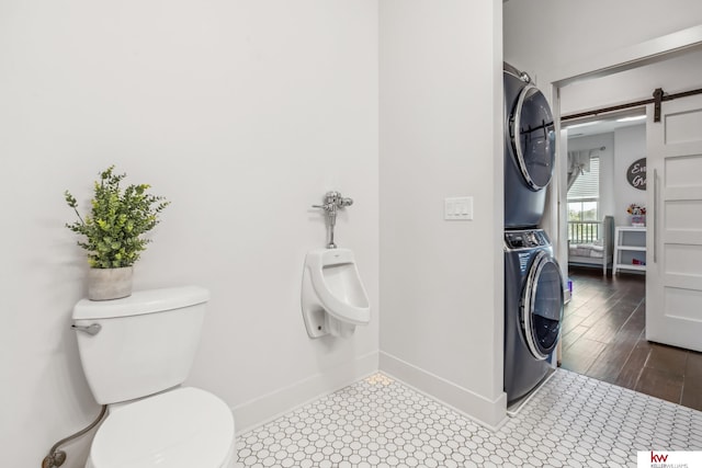 bathroom featuring toilet, stacked washing maching and dryer, and wood-type flooring