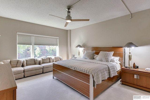 bedroom featuring light carpet, ceiling fan, and a textured ceiling