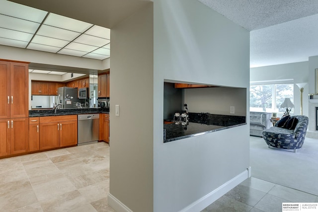 kitchen with dark stone counters, appliances with stainless steel finishes, sink, and light tile patterned floors