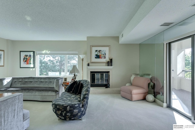 carpeted living room featuring a textured ceiling, a tiled fireplace, and a healthy amount of sunlight