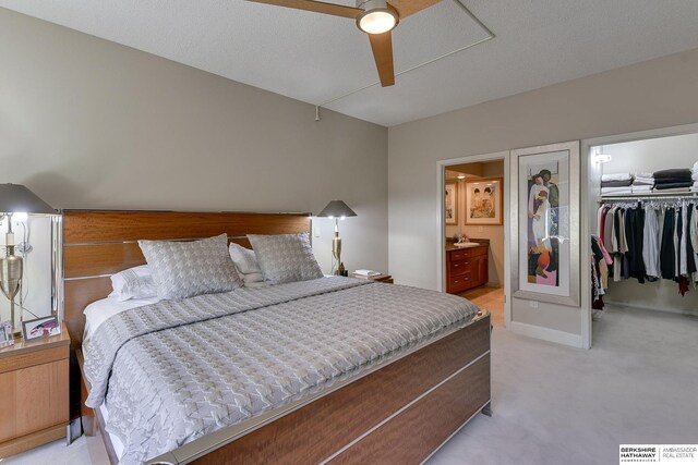 carpeted bedroom featuring a spacious closet, ceiling fan, a closet, ensuite bath, and a textured ceiling