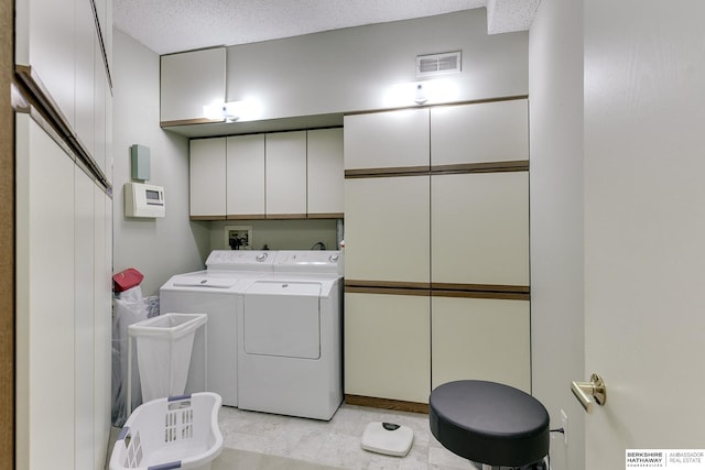 laundry room featuring cabinets, independent washer and dryer, and a textured ceiling