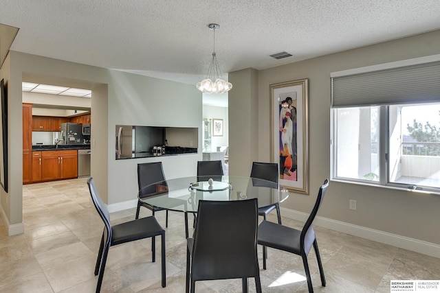 dining room featuring light tile patterned floors, a chandelier, and a textured ceiling