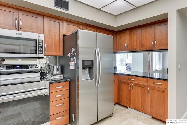 kitchen with appliances with stainless steel finishes and dark stone counters