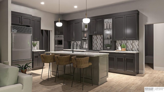 kitchen featuring decorative light fixtures, a center island with sink, stainless steel appliances, light hardwood / wood-style floors, and decorative backsplash