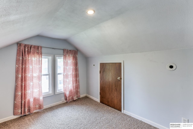 additional living space featuring carpet flooring, a textured ceiling, and vaulted ceiling