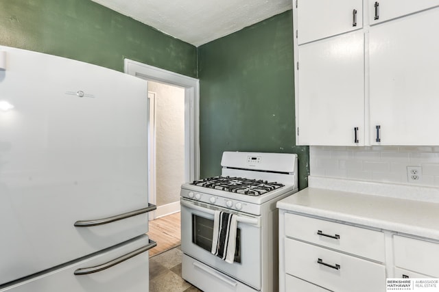 kitchen with decorative backsplash, white appliances, white cabinets, and light tile patterned floors