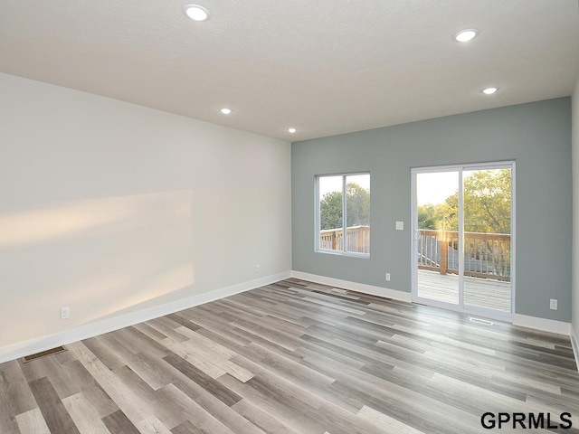 unfurnished room featuring light hardwood / wood-style floors and a textured ceiling