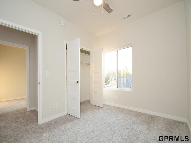 unfurnished bedroom with ceiling fan, light colored carpet, and a closet