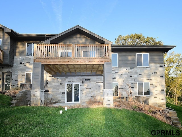 back of property featuring a balcony and a lawn