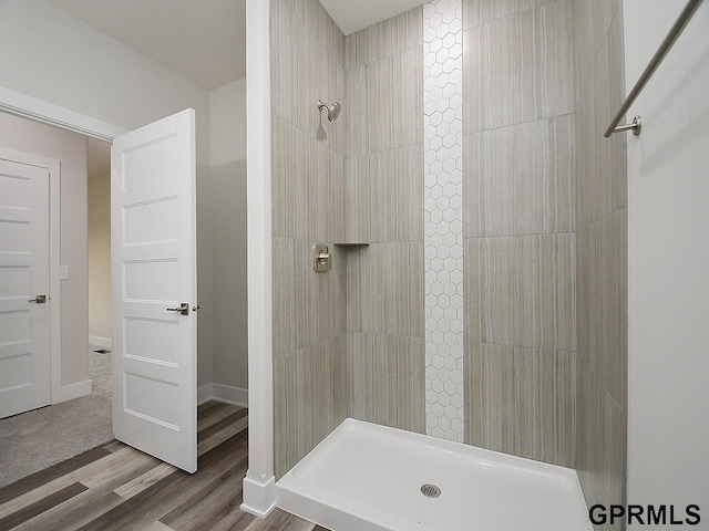 bathroom with a tile shower and hardwood / wood-style floors