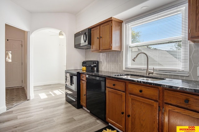 kitchen featuring ceiling fan, light hardwood / wood-style flooring, sink, backsplash, and black appliances