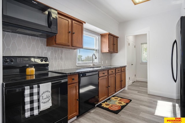 kitchen with black appliances, plenty of natural light, sink, and light hardwood / wood-style floors