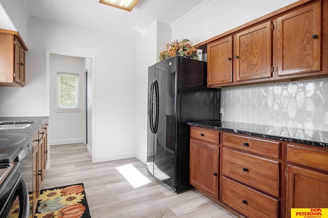 kitchen with black fridge, tasteful backsplash, light hardwood / wood-style flooring, dark stone counters, and crown molding