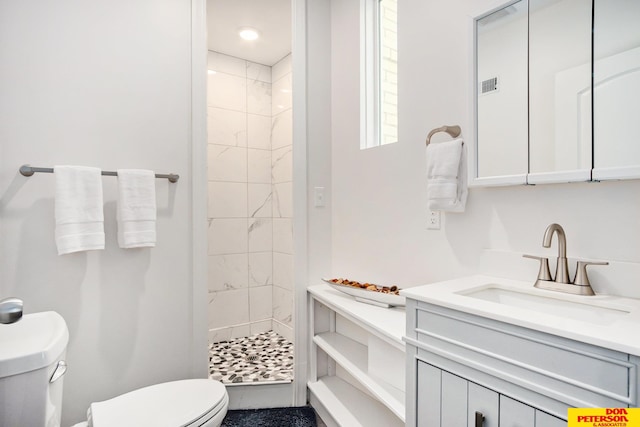 bathroom featuring a tile shower, vanity, toilet, and tile patterned floors