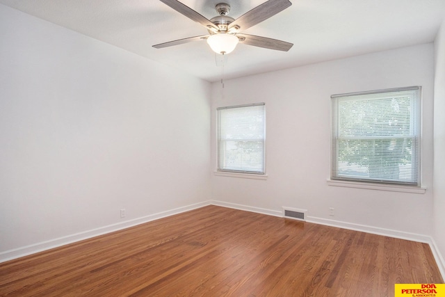 empty room featuring ceiling fan, hardwood / wood-style floors, and a healthy amount of sunlight