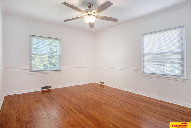 empty room featuring hardwood / wood-style flooring, a healthy amount of sunlight, ceiling fan, and crown molding