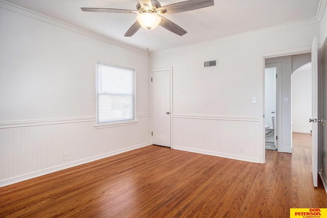 empty room with wood-type flooring, crown molding, and ceiling fan