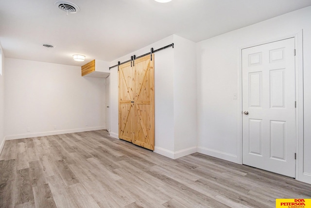 empty room with light hardwood / wood-style flooring and a barn door