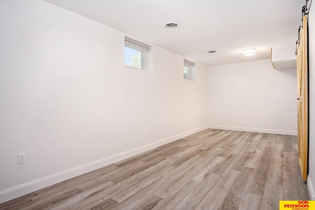 basement featuring a barn door and light hardwood / wood-style floors