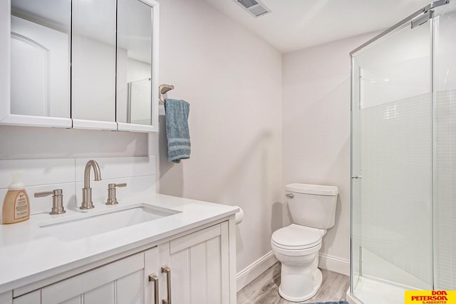 bathroom with hardwood / wood-style flooring, vanity, a shower with door, and toilet