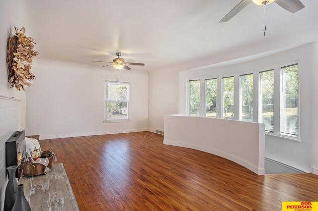 unfurnished living room with ceiling fan, dark hardwood / wood-style floors, and a healthy amount of sunlight