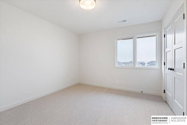 carpeted empty room featuring a textured ceiling