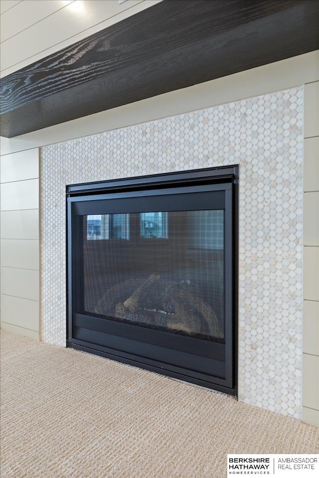 interior details with a tiled fireplace and carpet flooring