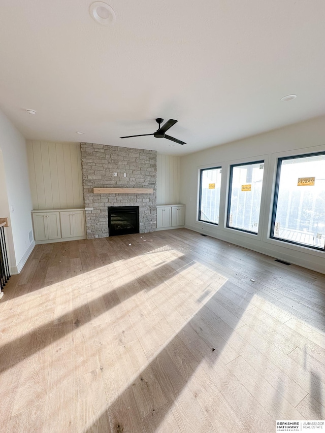 unfurnished living room featuring ceiling fan, a fireplace, and light hardwood / wood-style floors