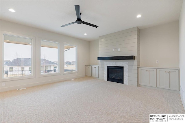 unfurnished living room with light carpet, a fireplace, and ceiling fan